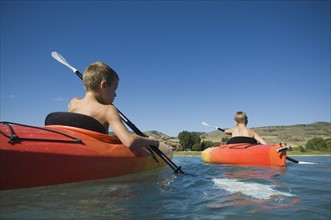 Brothers paddling in canoes on lake, Utah, United States. Date : 2007