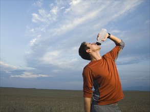 Man in athletic gear drinking water. Date : 2007