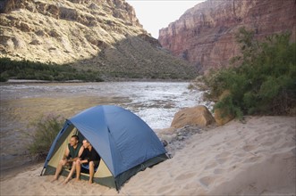 Couple in tent next to river, Colorado River, Moab, Utah, United States. Date : 2007