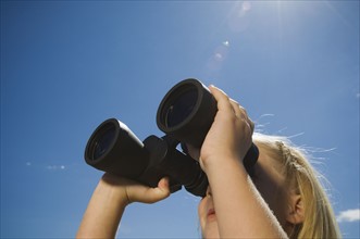Girl looking through binoculars, Utah, United States. Date : 2007