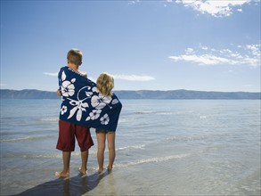 Brother and sister wrapped in beach towel, Utah, United States. Date : 2007