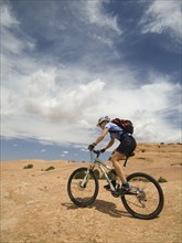 Woman riding mountain bike in desert. Date : 2007