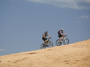 Couple riding mountain bikes in desert. Date : 2007