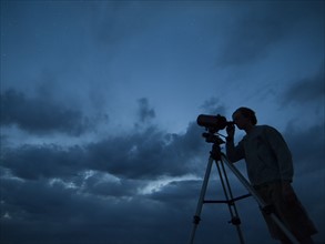 Man using telescope on tripod. Date : 2007