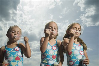 Three young sisters blowing bubbles. Date : 2007
