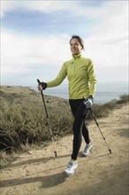 Hispanic woman pole walking along coast in California, United States. Date : 2007