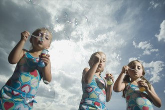 Three young sisters blowing bubbles. Date : 2007
