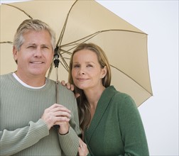 Couple standing under umbrella.
