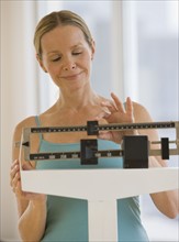 Woman weighing self on scale.