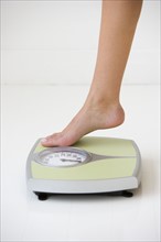 Woman stepping on scale.