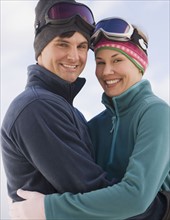 Couple in ski goggles hugging.