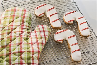 Candy cane cookies and oven mitt on cooling rack.