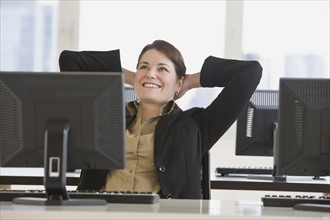 Businesswoman with hands behind head.