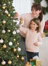 Mother and daughter decorating Christmas tree.