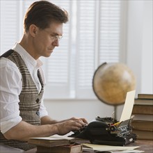 Man typing on antique typewriter.