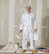 Male painter holding paint roller and paint can.