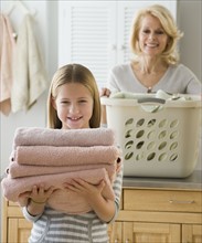 Girl holding stack of folded towels.