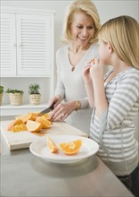 Grandmother and granddaughter cutting oranges.