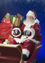 Santa Claus in sleigh with bag of toys.