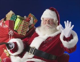 Santa Claus next to bag of toys.