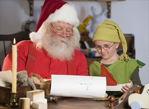 Santa Claus and elf reading list of names.