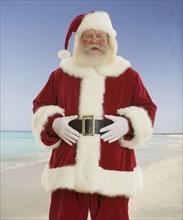 Santa Claus laughing at beach.