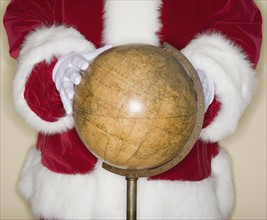 Santa Claus with hands on globe.