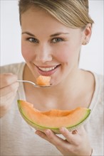 Woman eating melon wedge.