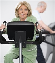Senior woman riding on exercise machine.