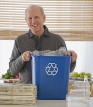 Senior man holding recycling bin.