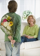 Grandson surprising grandmother with flowers.