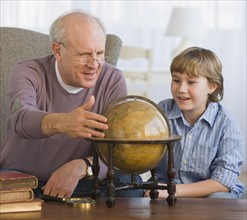 Grandfather and grandson looking at globe.
