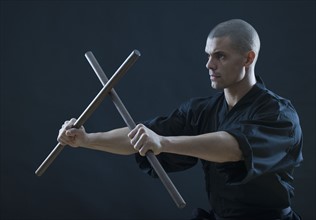 Hispanic male holding sticks in fighting stance.