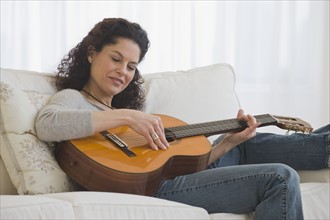 Hispanic woman playing guitar.