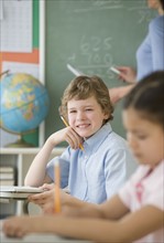 Boy holding pencil at school desk.
