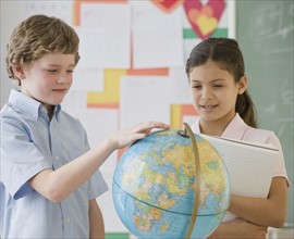Multi-ethnic school children looking at globe.