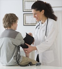 Hispanic female doctor taking child’s blood pressure.