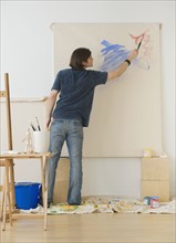 Man painting on easel.