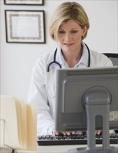 Female doctor typing on computer.