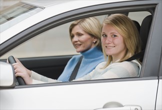 Teenaged girl driving with mother.