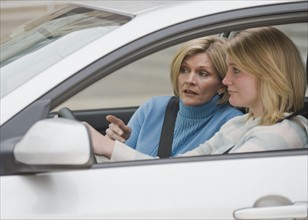 Mother teaching teenaged daughter to drive.