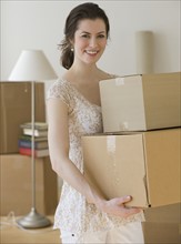 Woman carrying stack of moving boxes.