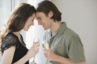 Couple holding champagne and touching foreheads.