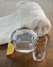 Water jug and glass next to rolled towel.