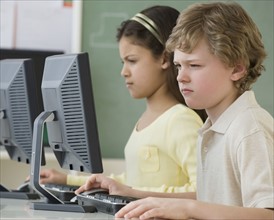 Multi-ethnic school children looking at computers.
