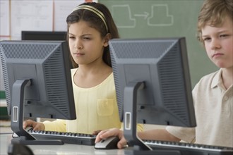 Multi-ethnic school children looking at computers.