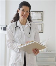 Hispanic female doctor holding chart.