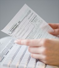 Woman holding tax form over keyboard.