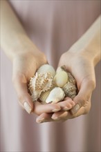 Woman holding handful of seashells.