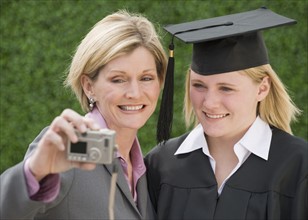 Mother and graduate daughter taking own photograph.